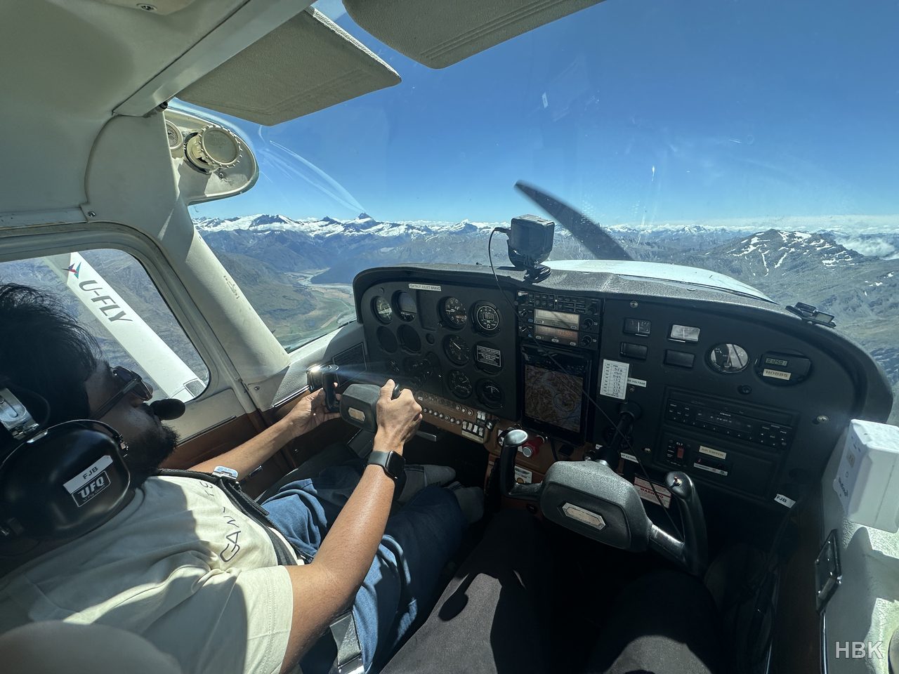 Naveed holding aircraft controls with mountains beyond the windscreen