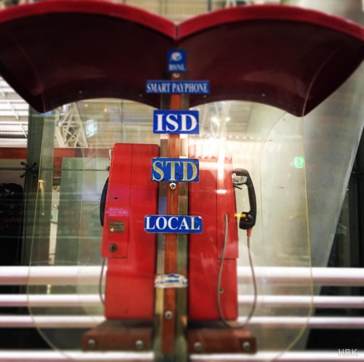 Red payphones behind glass with local and international call signs