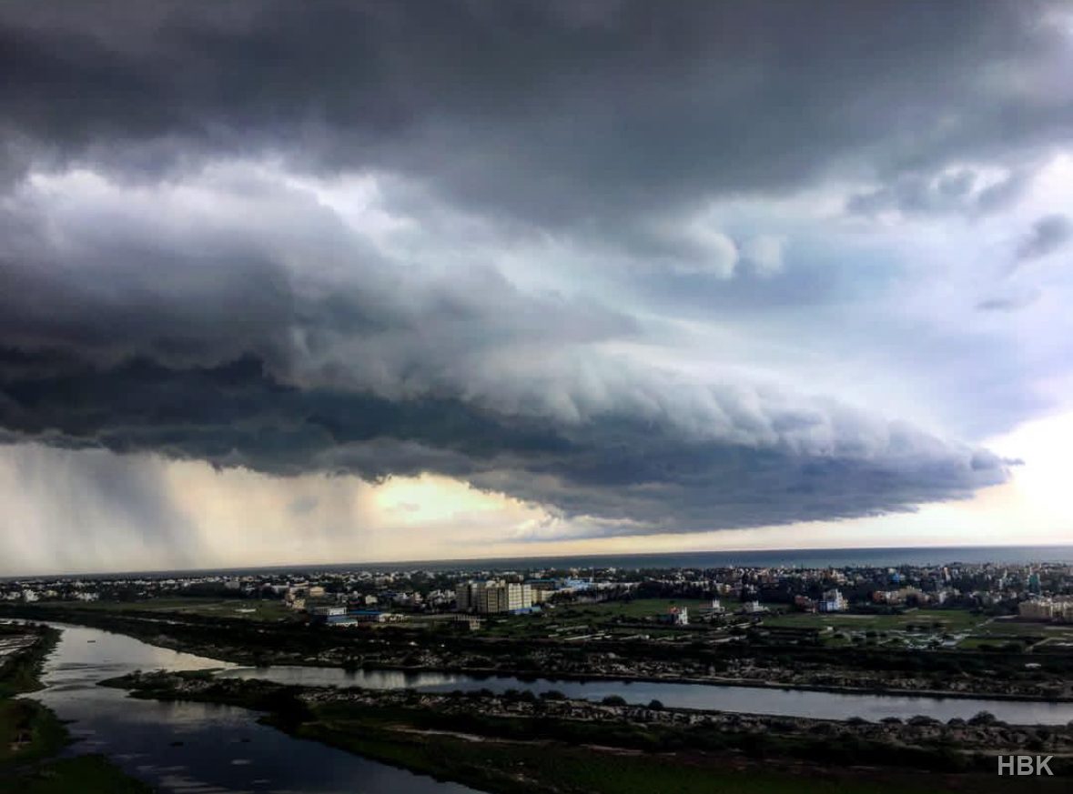 Storm clouds and rainfall over a city and river