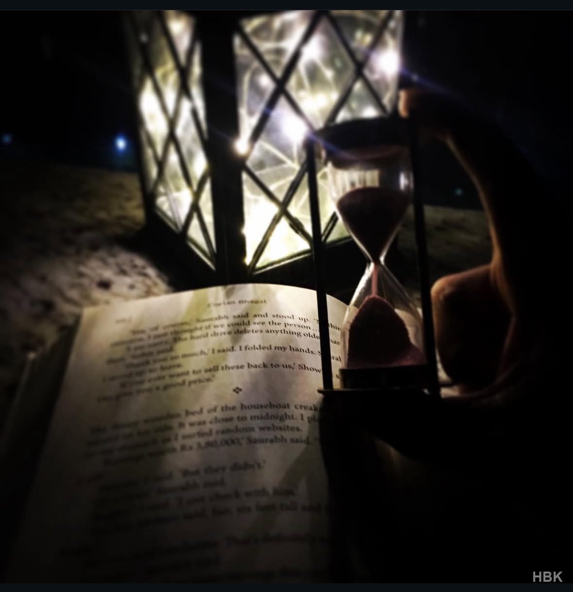 Hourglass beside an open book and glowing lantern