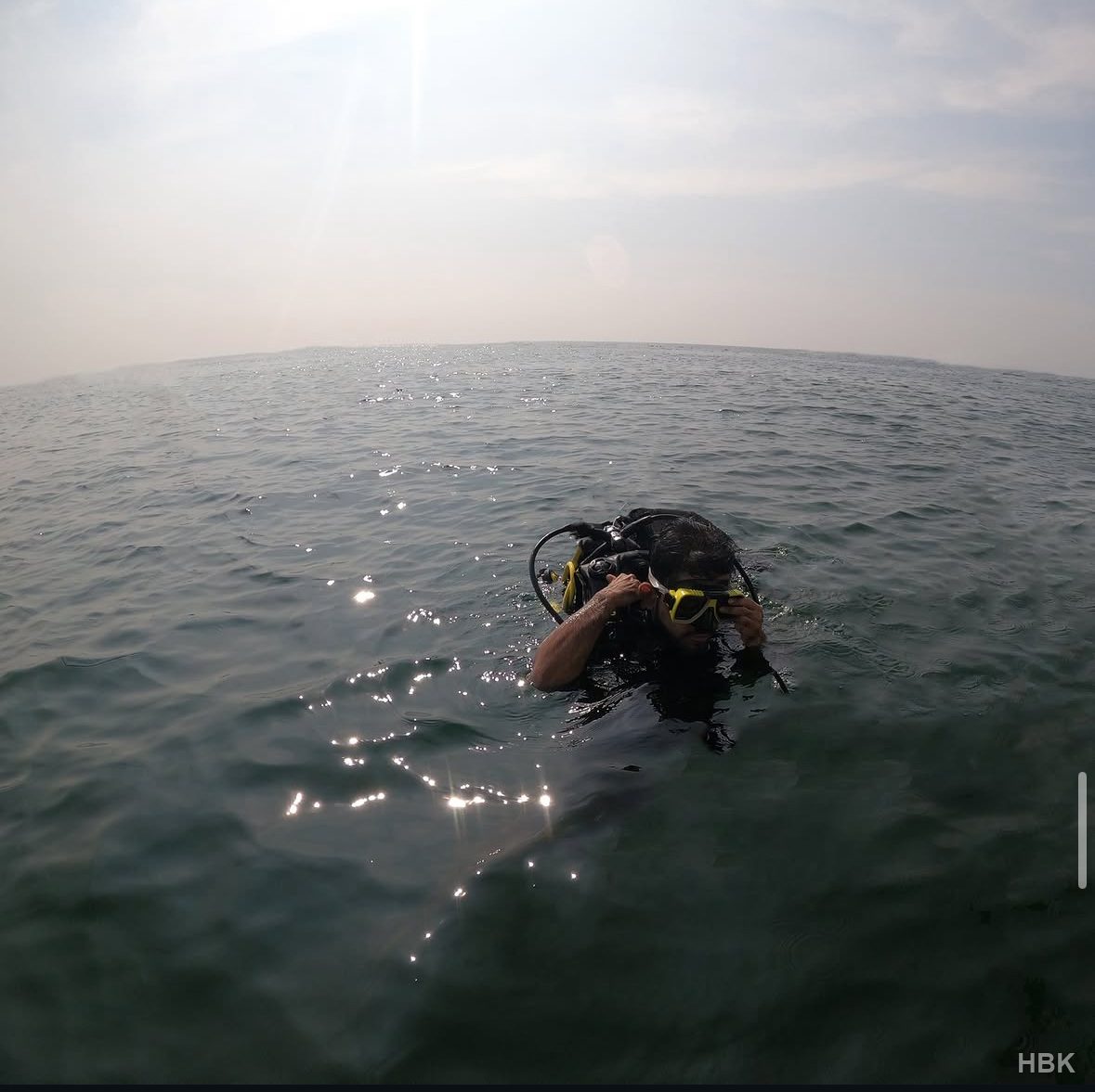 Diver adjusting a mask while wearing scuba equipment at the sea surface